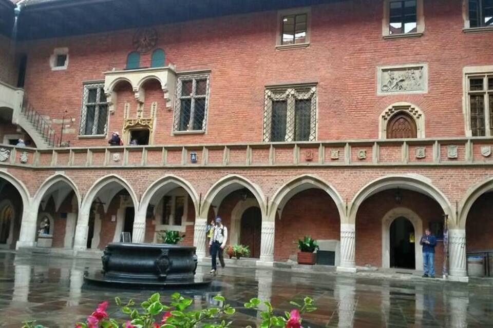 Un patio con una fuente, muros de ladrillo y senderos con arcos.