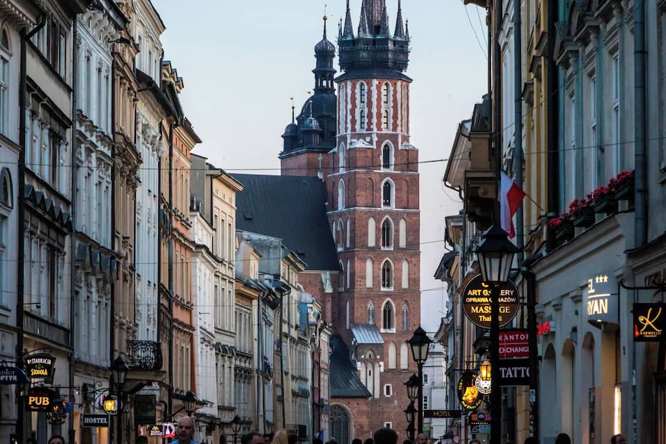 A cobblestone street lined with historic buildings and a prominent church tower.