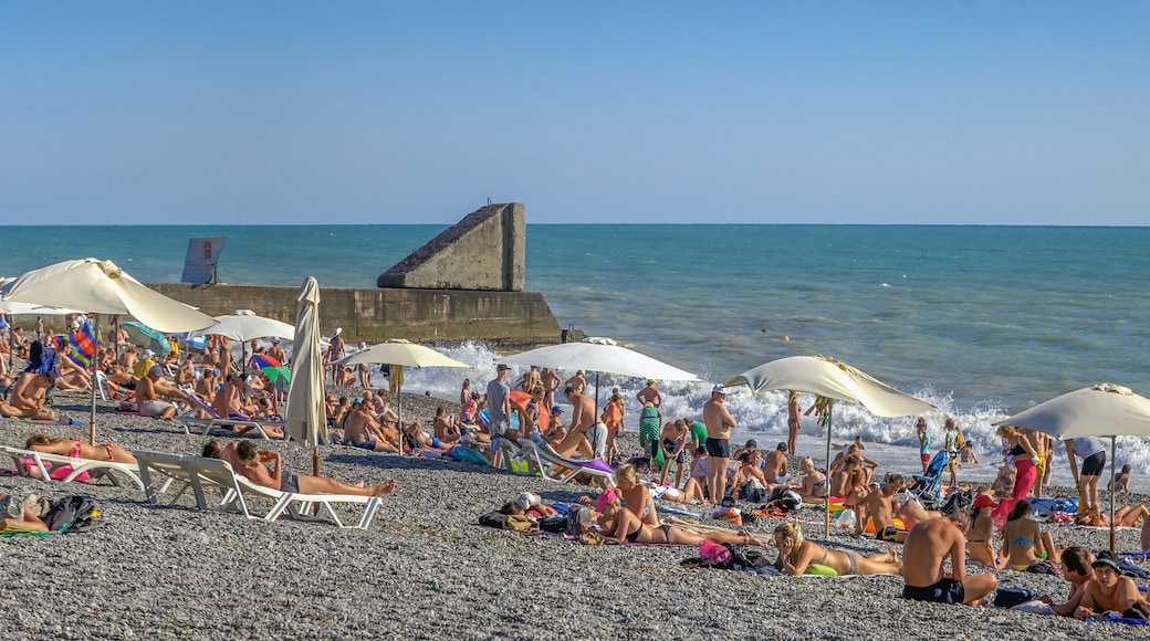 Una playa concurrida, con muchos sombrillas y gente tomando el sol.
