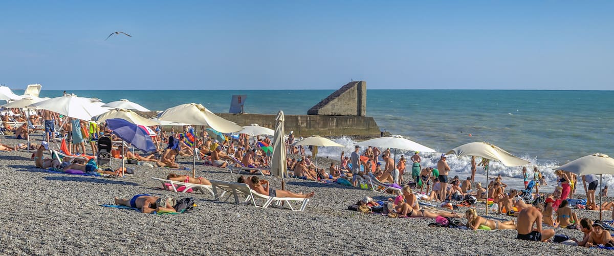 A crowded beach with numerous umbrellas and people sunbathing.