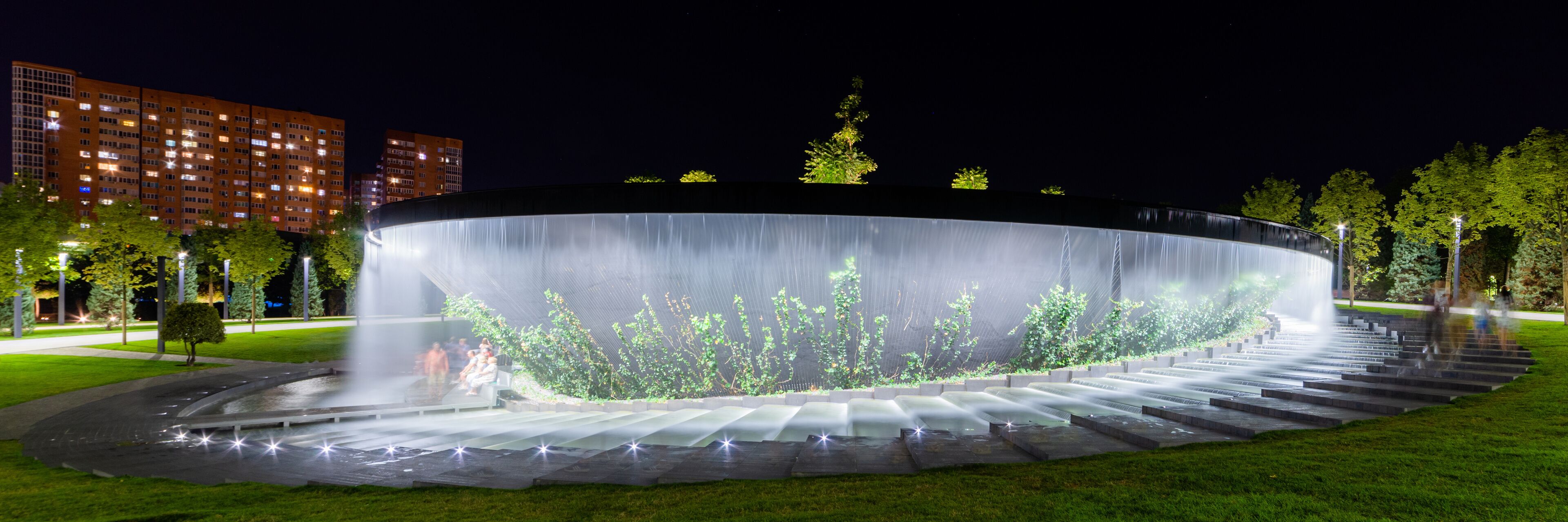 Waterfall flows in streams into granite bed of artificial river. Fountain in form of huge bowl.