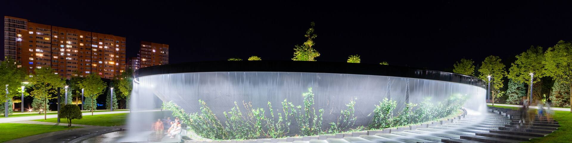 Waterfall flows in streams into granite bed of artificial river. Fountain in form of huge bowl.