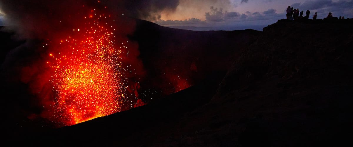 Una erupción volcánica con lava descendiendo por la ladera de una montaña.