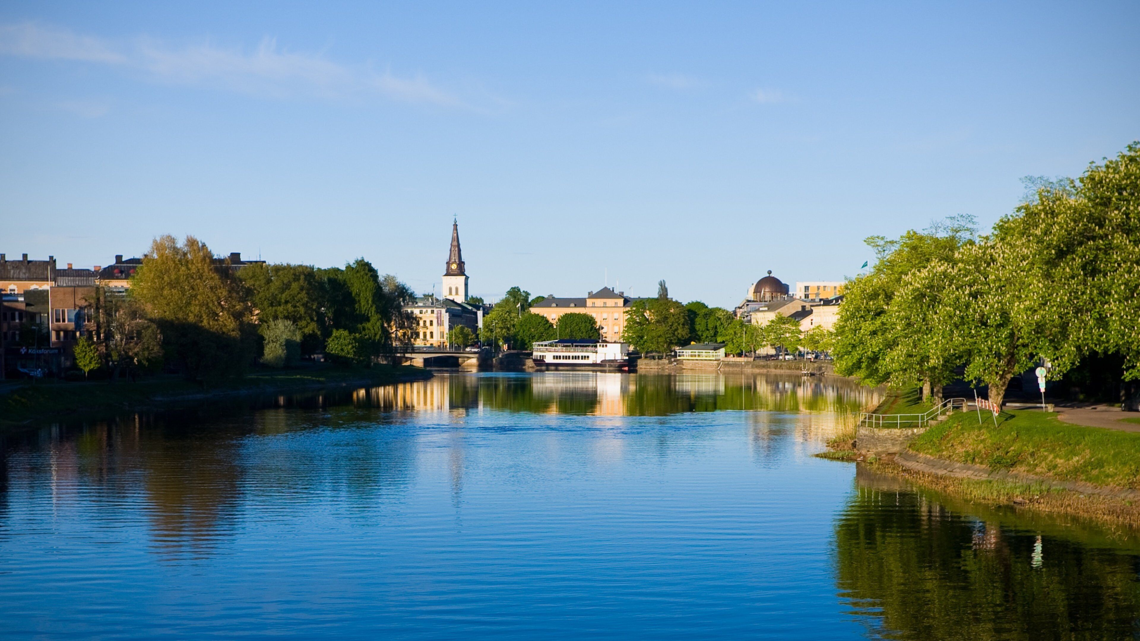 A river with a boat, a church, and buildings along the riverbank.
