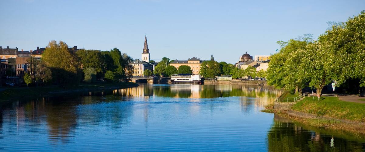 A river with a boat, a church, and buildings along the riverbank.