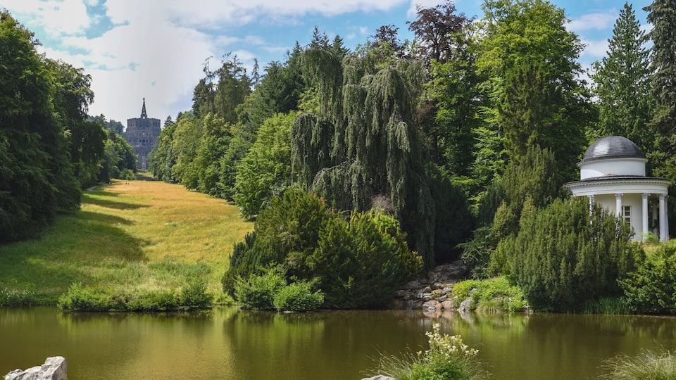 A lake surrounded by dense trees and a gazebo.