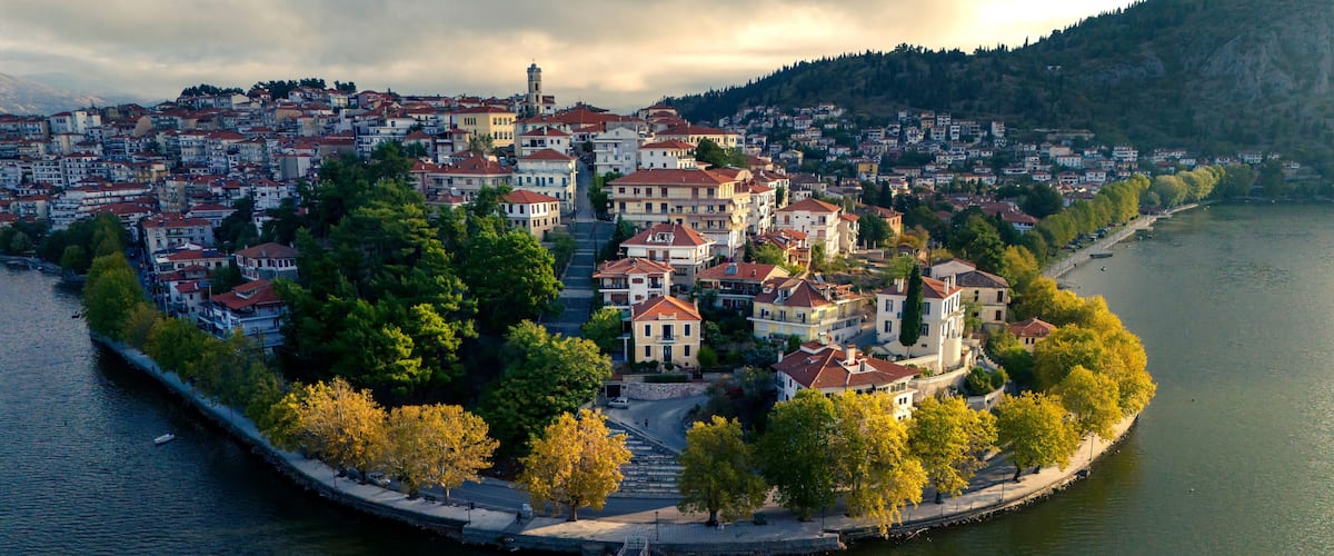 A riverside town with historic buildings, a bridge, and autumn foliage.