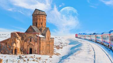 Red diesel train (East express) in motion at the snow covered railway platform - Ani Ruins, Ani is a ruined and uninhabited medieval Armenian city "Elements of this image furnished by NASA "
