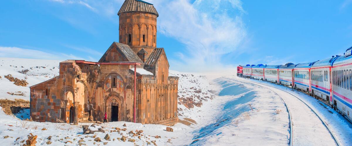 A snow-covered landscape with a historic church and a train track.