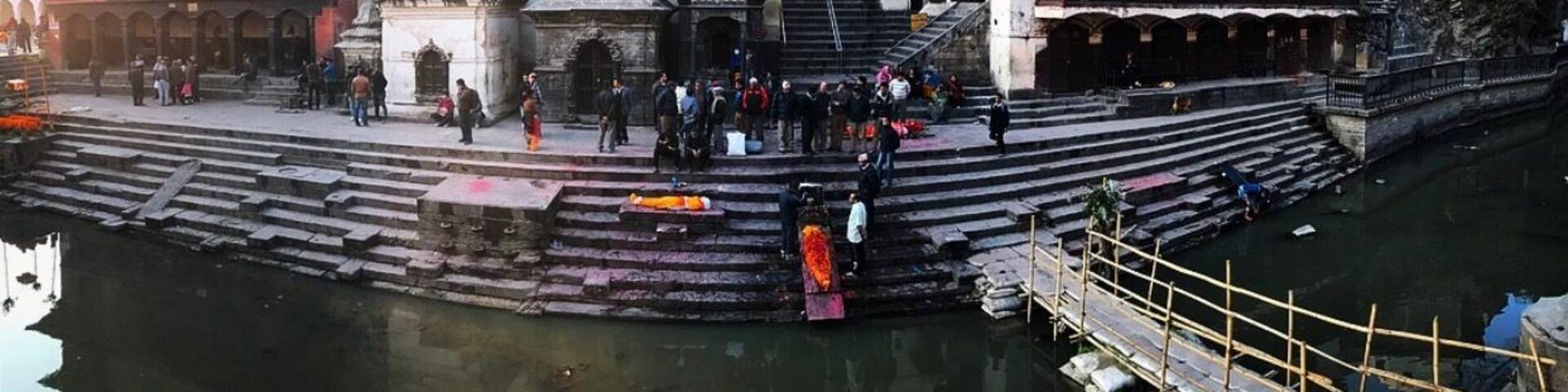 A historic temple complex with steps leading down to a river, surrounded by traditional buildings.