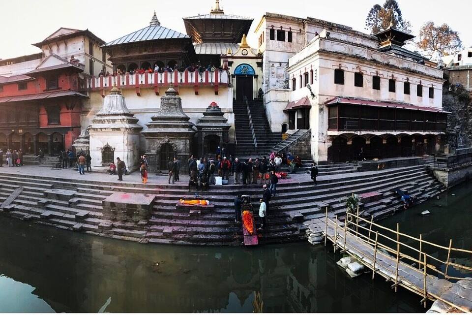 A historic temple complex with steps leading down to a river, surrounded by traditional buildings.