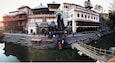 A historic temple complex with steps leading down to a river, surrounded by traditional buildings.