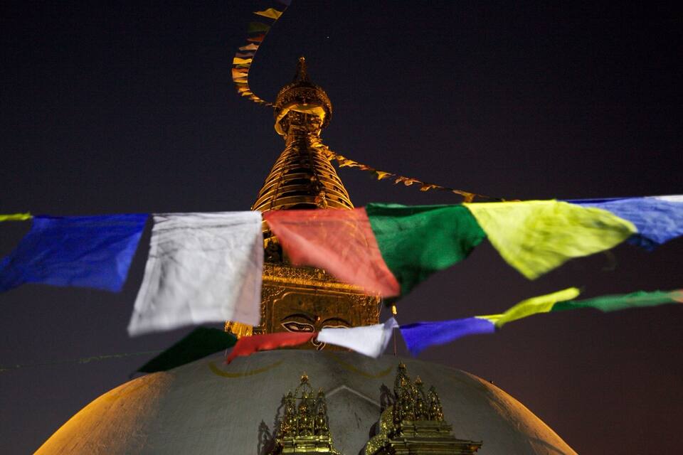 Una estupa dorada con banderas de oración al frente.