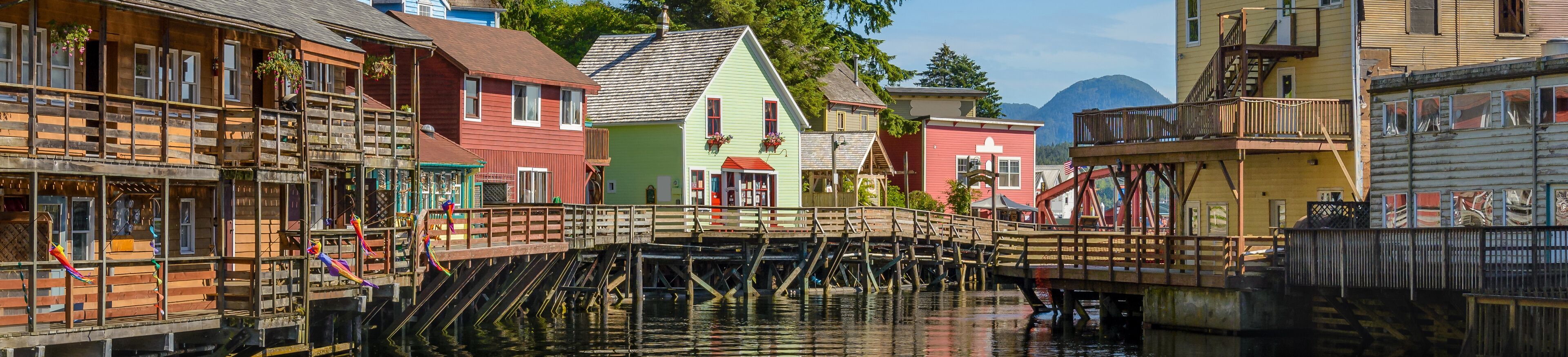 A wooden bridge over water with colorful buildings on either side.