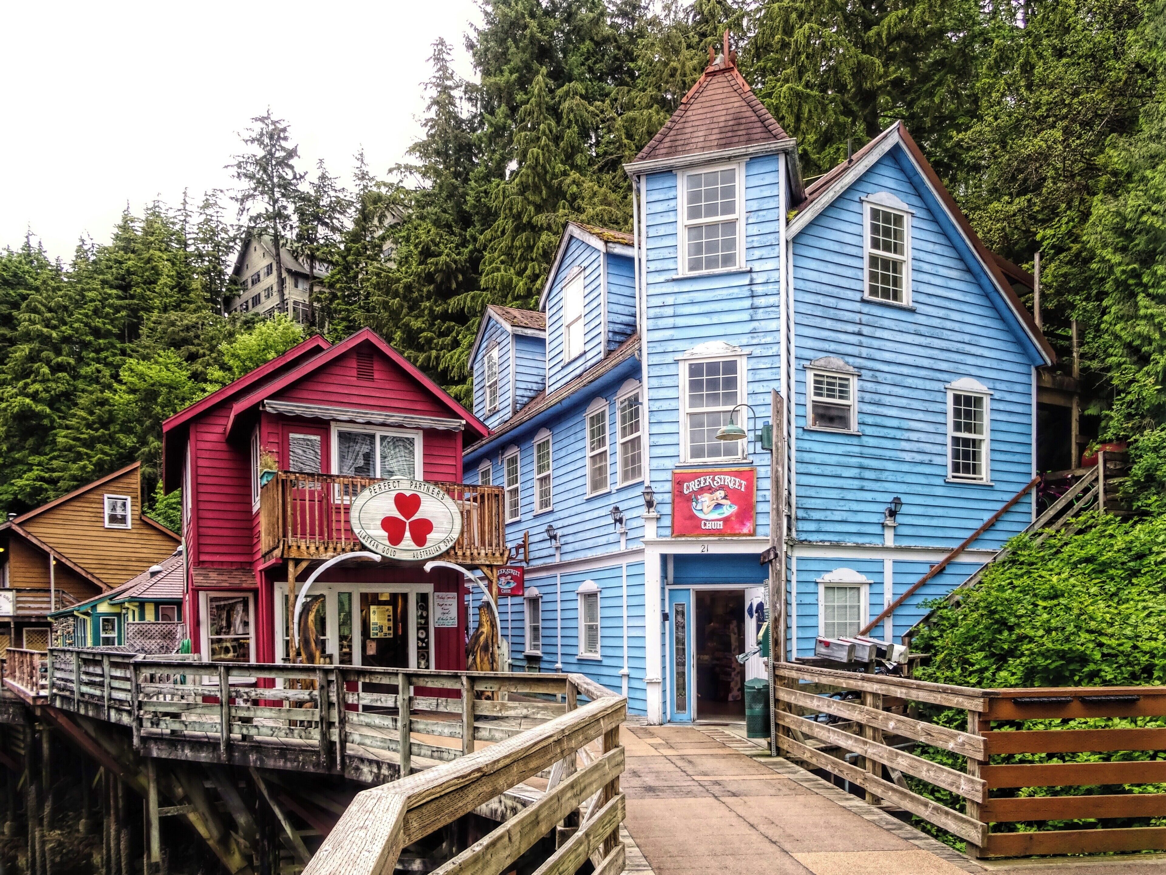 A wooden bridge leading to a blue building with a red sign.