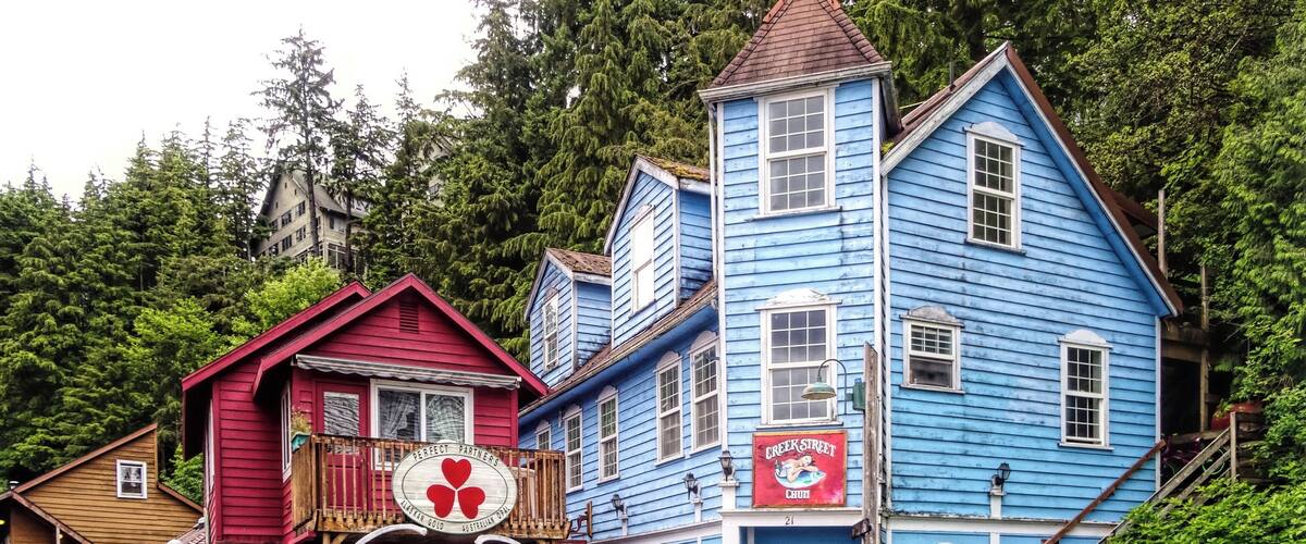 A wooden bridge leading to a blue building with a red sign.