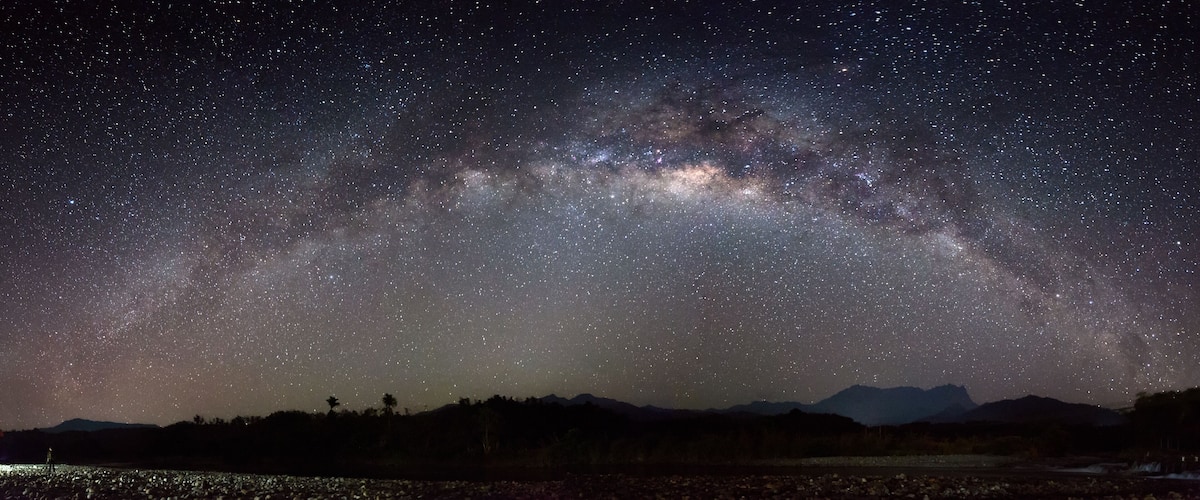 A starry night sky over a mountainous landscape.
