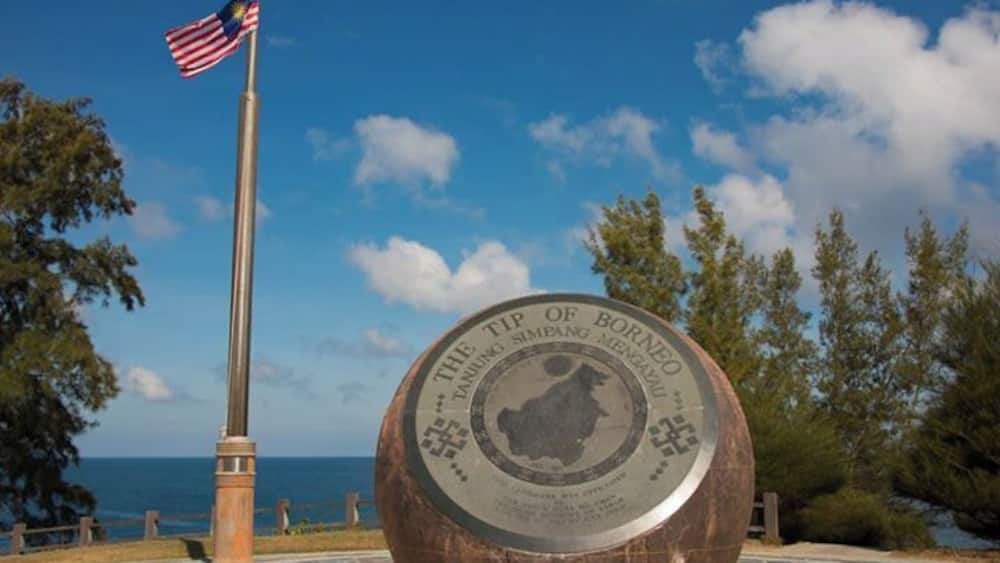 A monument with an American flag, surrounded by trees and a clear sky.