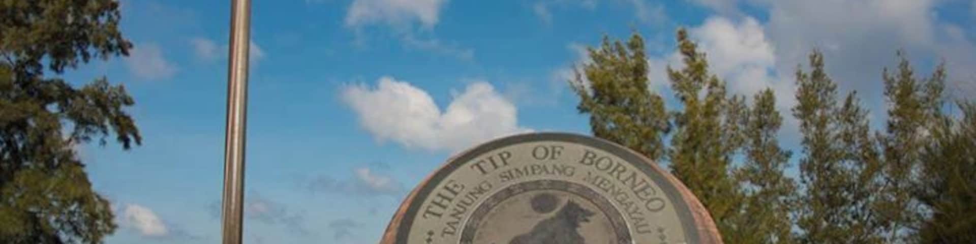 Un monumento con una bandera estadounidense, rodeado de árboles y un cielo despejado.