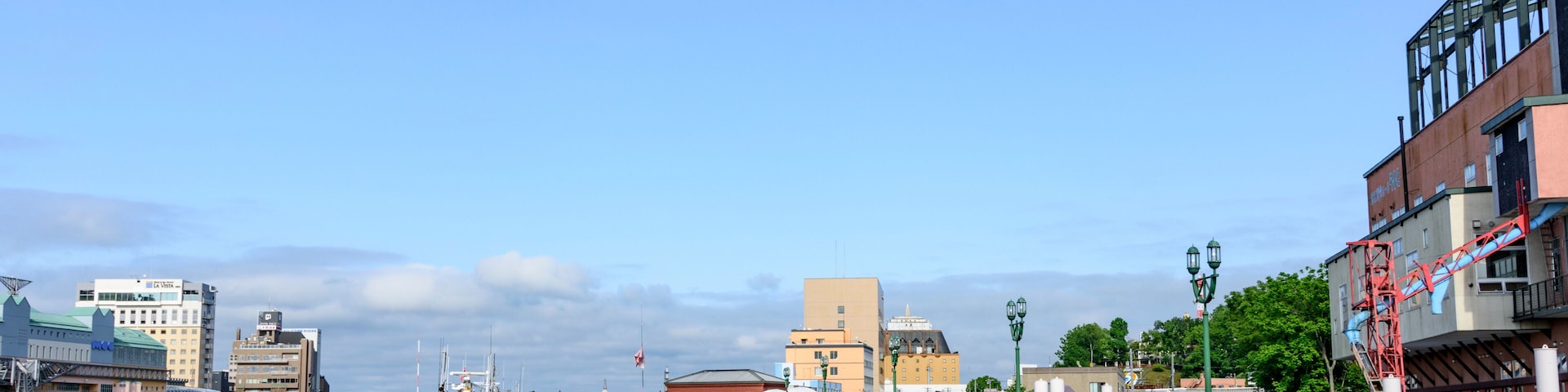 A waterfront promenade with buildings, a clear sky, and a calm river.