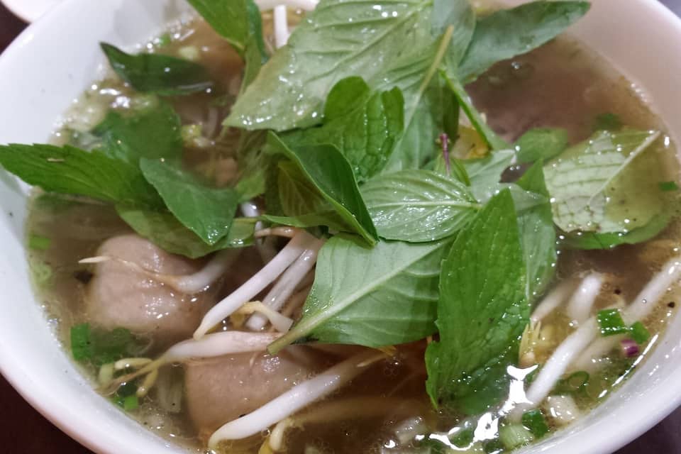Een kom Vietnamese pho met noedels, kruiden en vlees.