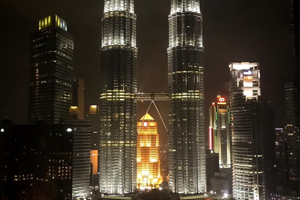 The Petronas Twin Towers at night, illuminated with lights.