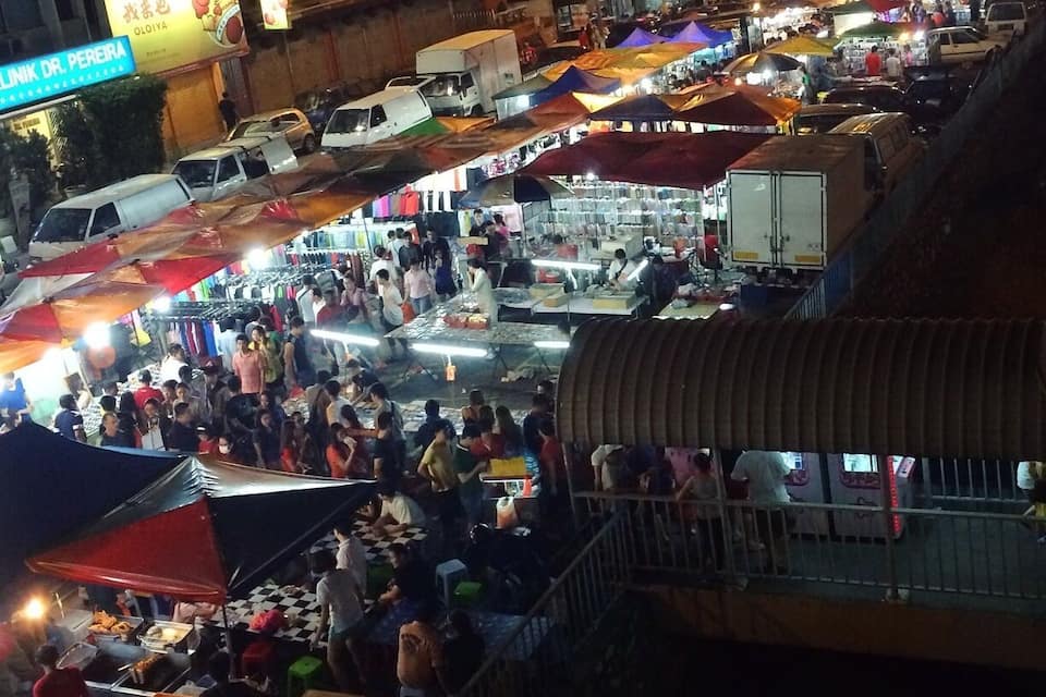 Un marché nocturne animé, avec de nombreux étals et beaucoup de monde.