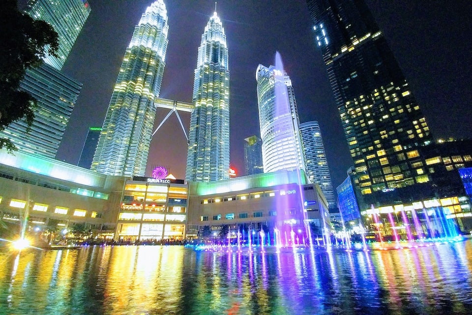 The Petronas Twin Towers illuminated at night with reflections on the water.