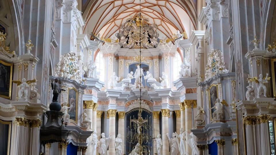 Interno di una chiesa decorata, con soffitti alti, sculture elaborate e file di panche.