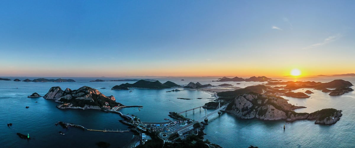 A coastal sunset with a bridge connecting islands.