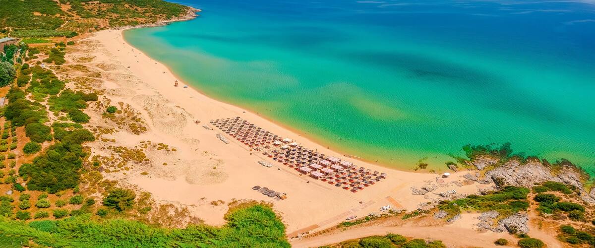 A beach with clear turquoise waters and a sandy shore.