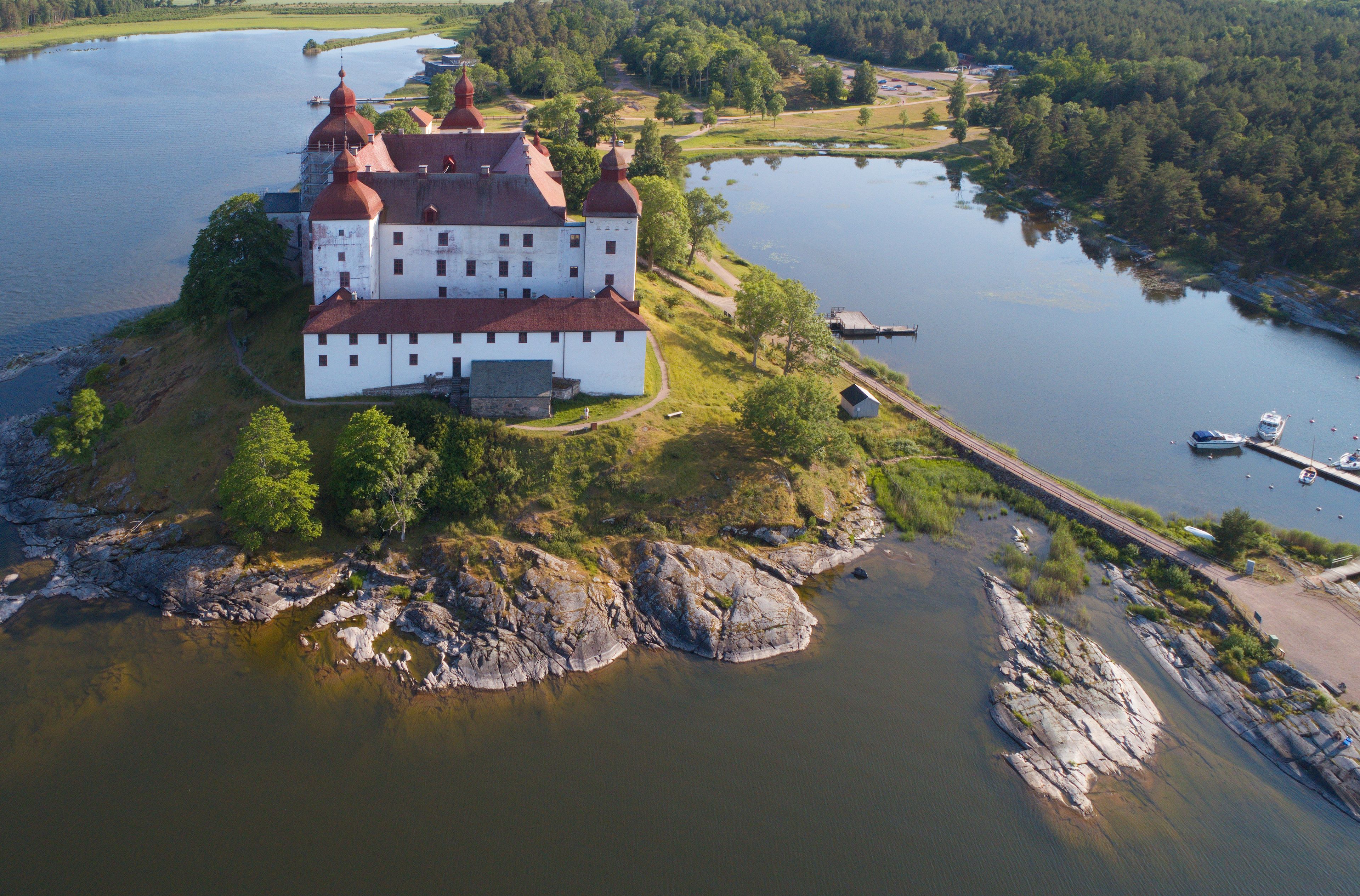 A large white building with red roofs on a small island surrounded by water.