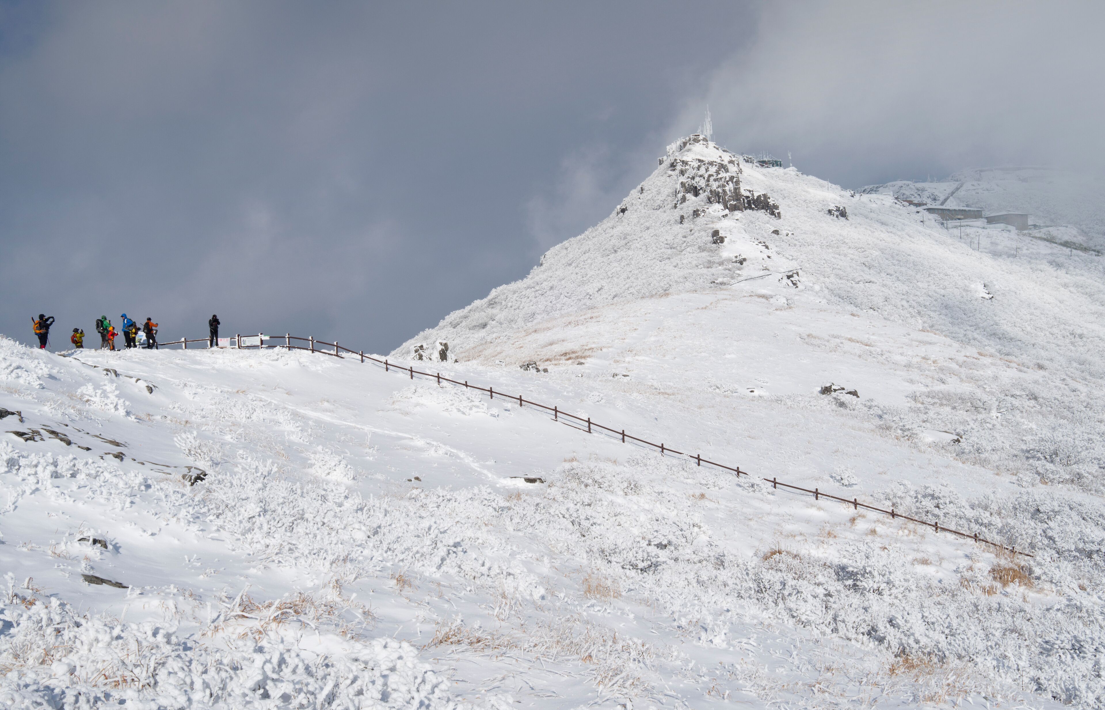 Mudeungsan National Park, Gwangju, South Korea - February 5, 2015: Hikers are standing besides snow covered Inwangbong Peak