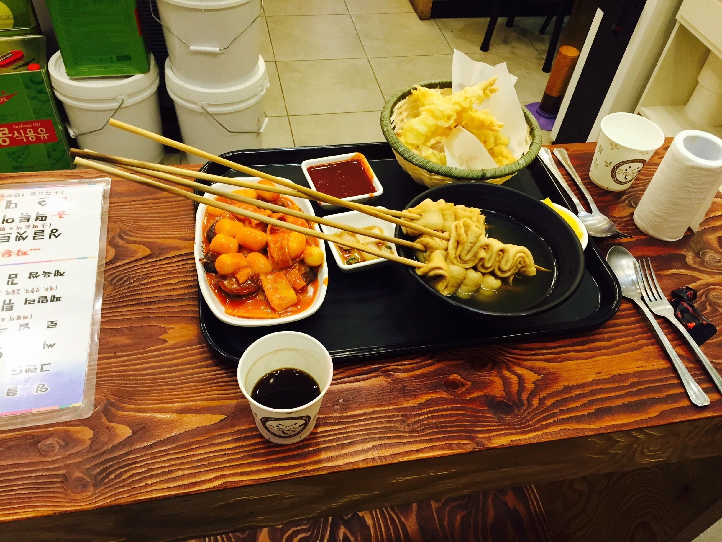 A tray with various dishes, chopsticks, a cup of tea, and a menu.