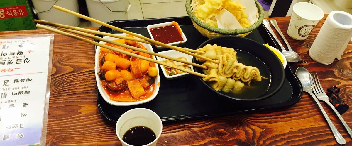 A tray with various dishes, chopsticks, a cup of tea, and a menu.