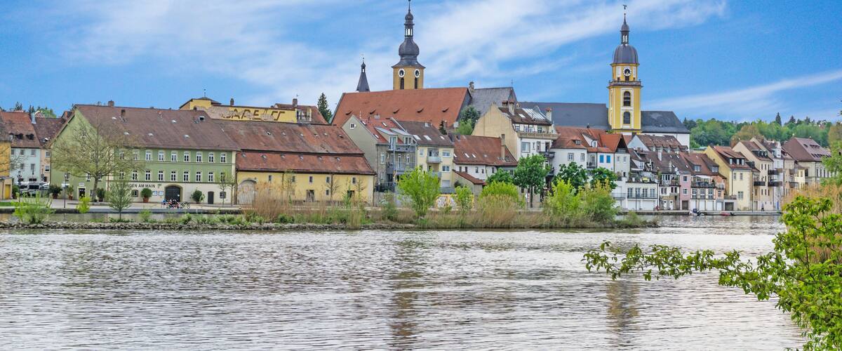 A riverside town with historic buildings and a prominent clock tower.