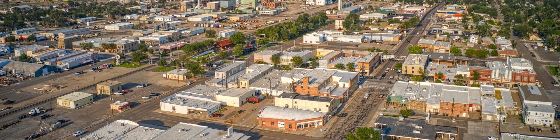An aerial view of a town with industrial buildings, a large grain elevator, and a prominent church steeple.
