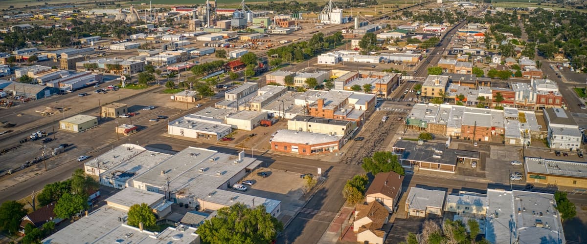 An aerial view of a town with industrial buildings, a large grain elevator, and a prominent church steeple.