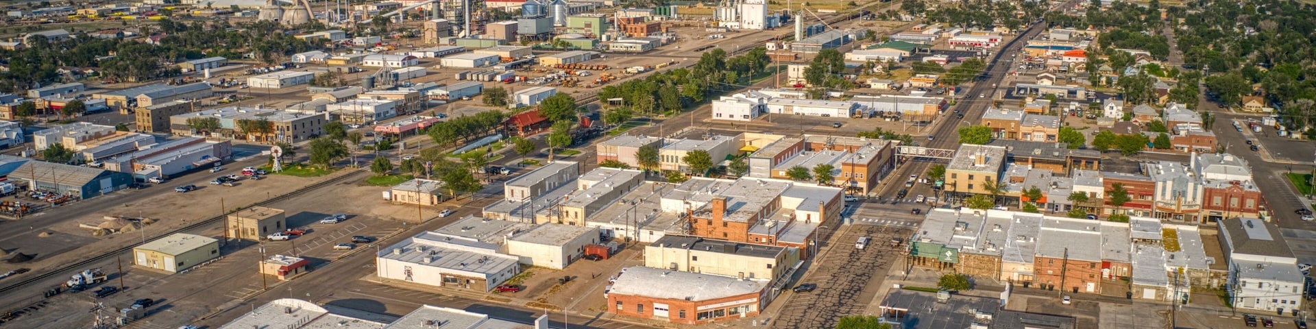 An aerial view of a town with industrial buildings, a large grain elevator, and a prominent church steeple.