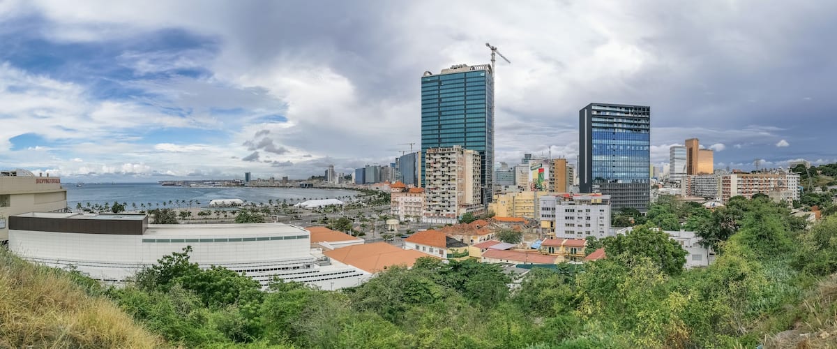 A coastal cityscape with modern skyscrapers, a beach, and lush greenery.