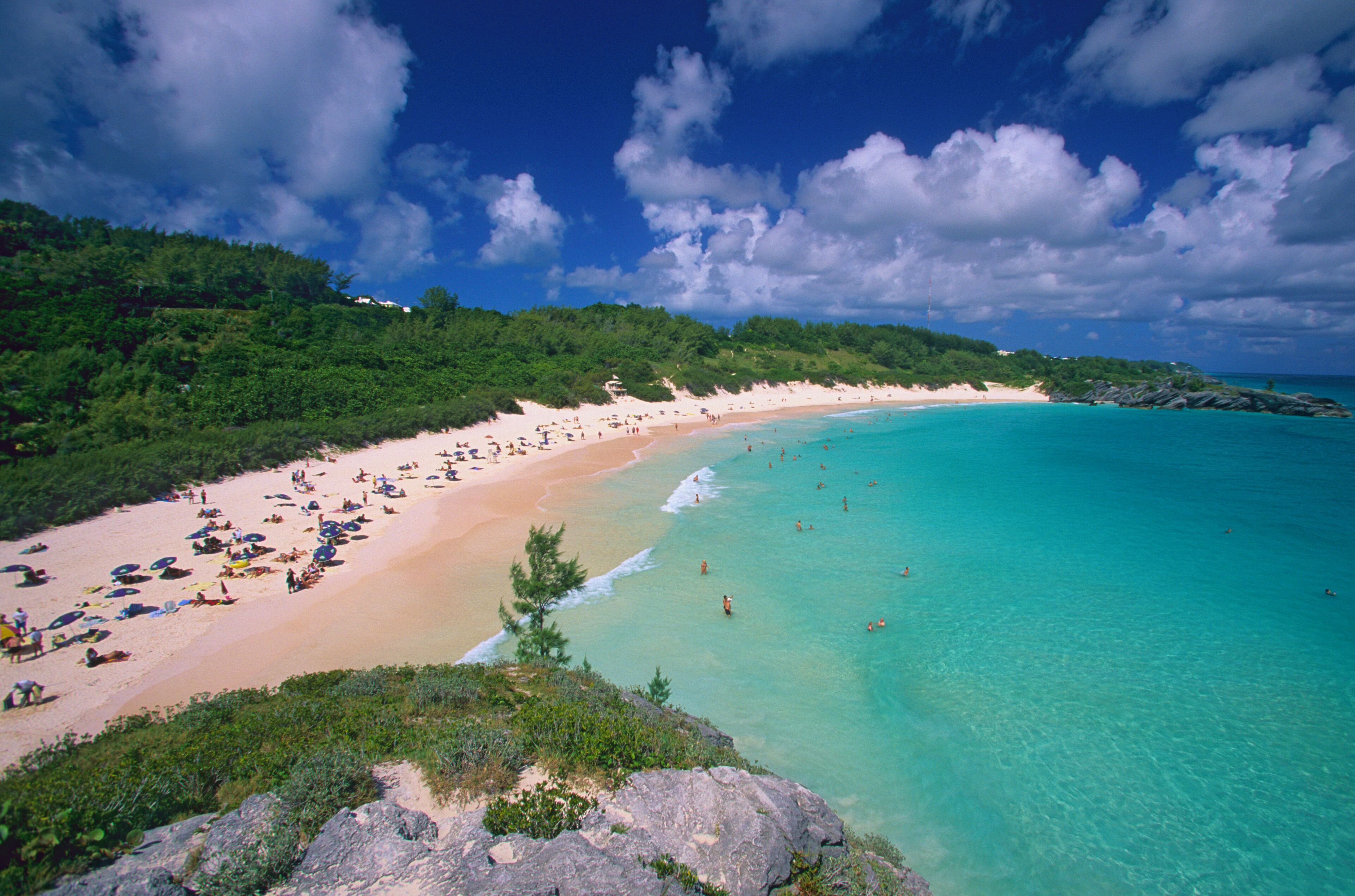Una playa tropical con aguas turquesas cristalinas, orillas de arena y exuberante vegetación.