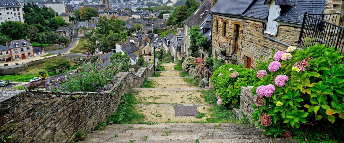 A stone staircase leading down a hillside with a view of a town in the distance.