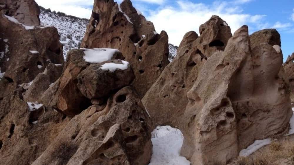 Un paysage rocheux parsemé de plaques de neige et présentant des cavités dans les formations rocheuses.