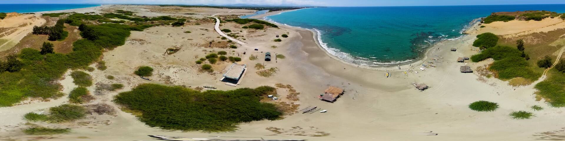 A coastal landscape with a sandy beach, a winding path, and scattered structures.