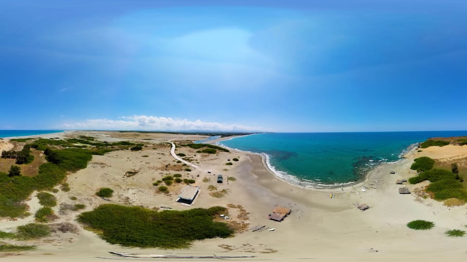 A coastal landscape with a sandy beach, a winding path, and scattered structures.