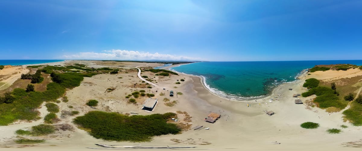 A coastal landscape with a sandy beach, a winding path, and scattered structures.