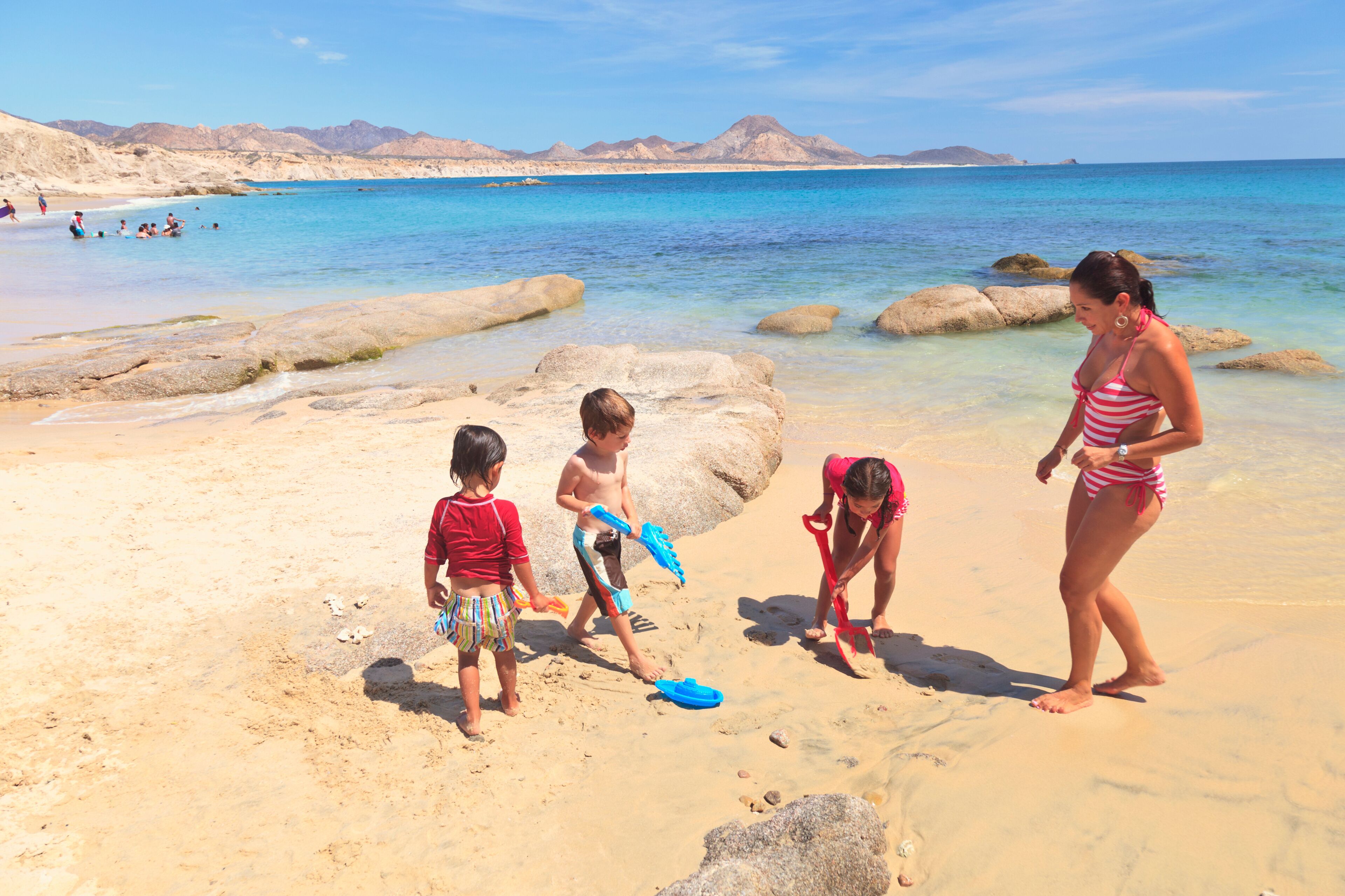 A Mother Plays With Her Three Children On A Beach; San Jose Del Cabo, Baja California Sur, Mexico
