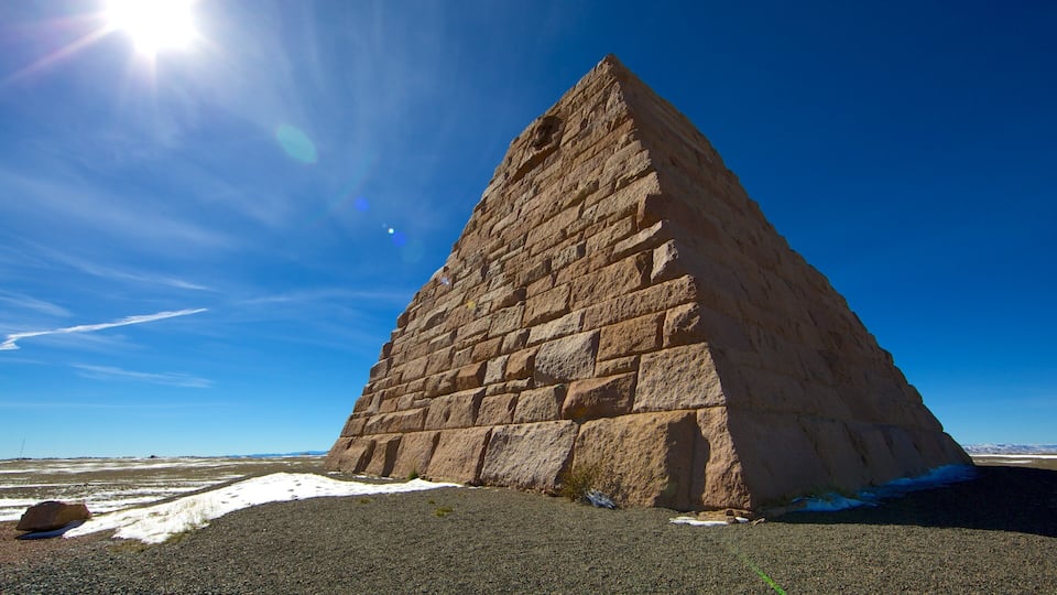 A large stone pyramid in a desert landscape with snow patches.