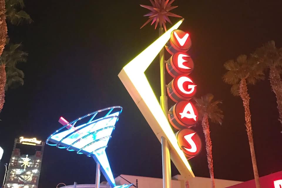 The iconic Vegas sign with a star on top, neon lights, and palm trees.