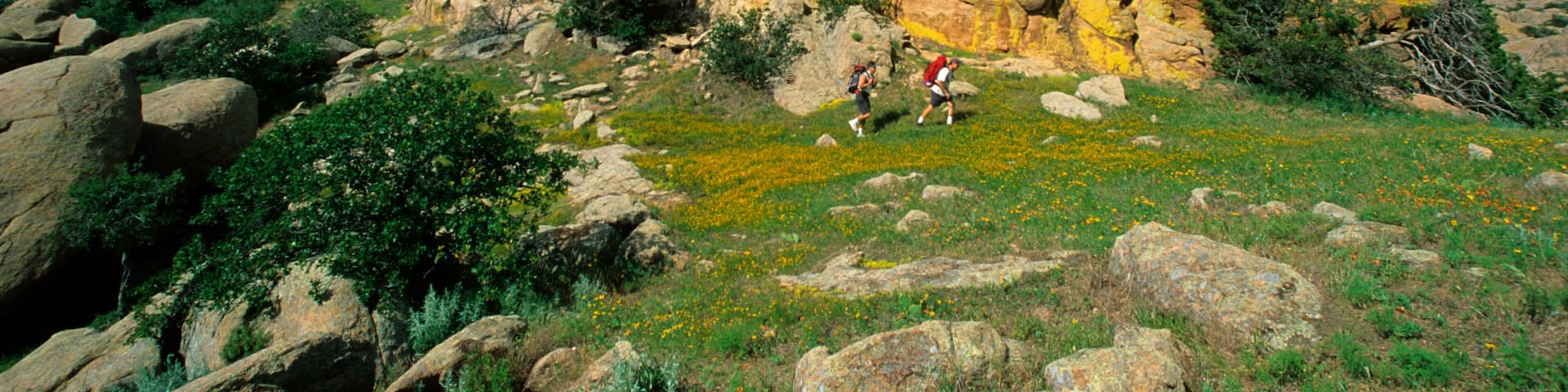 Hikers below colorful granite dome in the Wichita Wildlife Refuge near Lawton, OK.